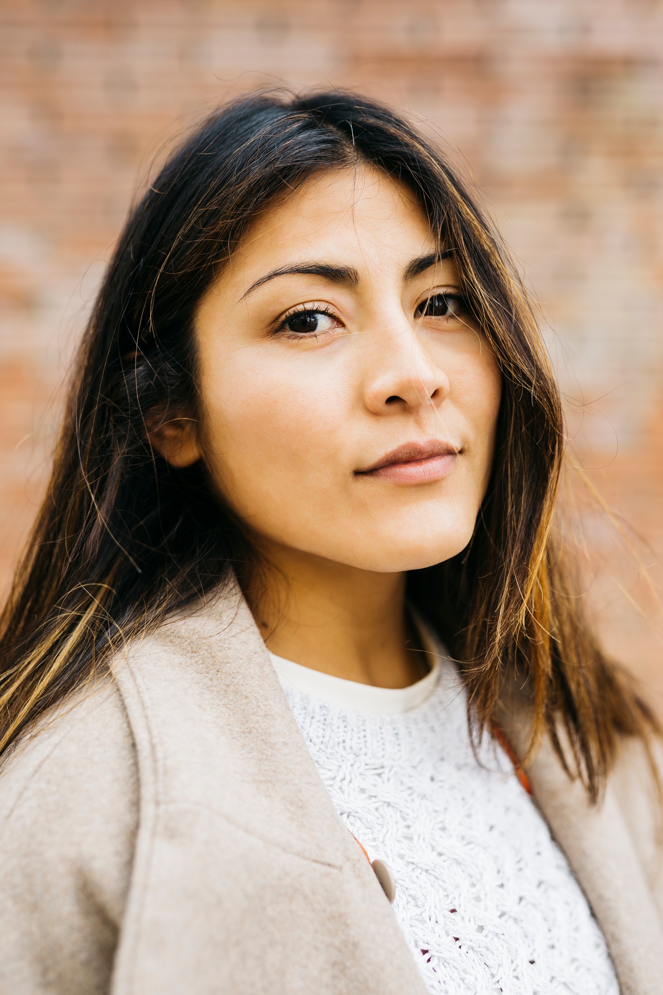 Young latin woman posing with brick wall background